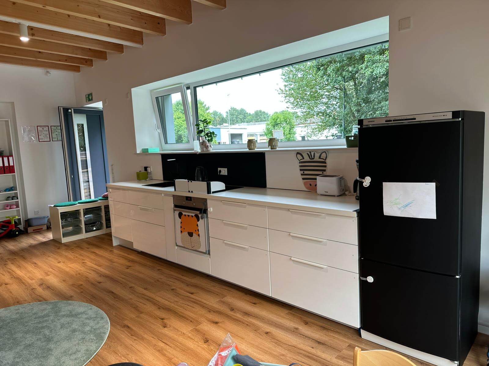 Küchenzeile in weiß mit hellen Fenstern.